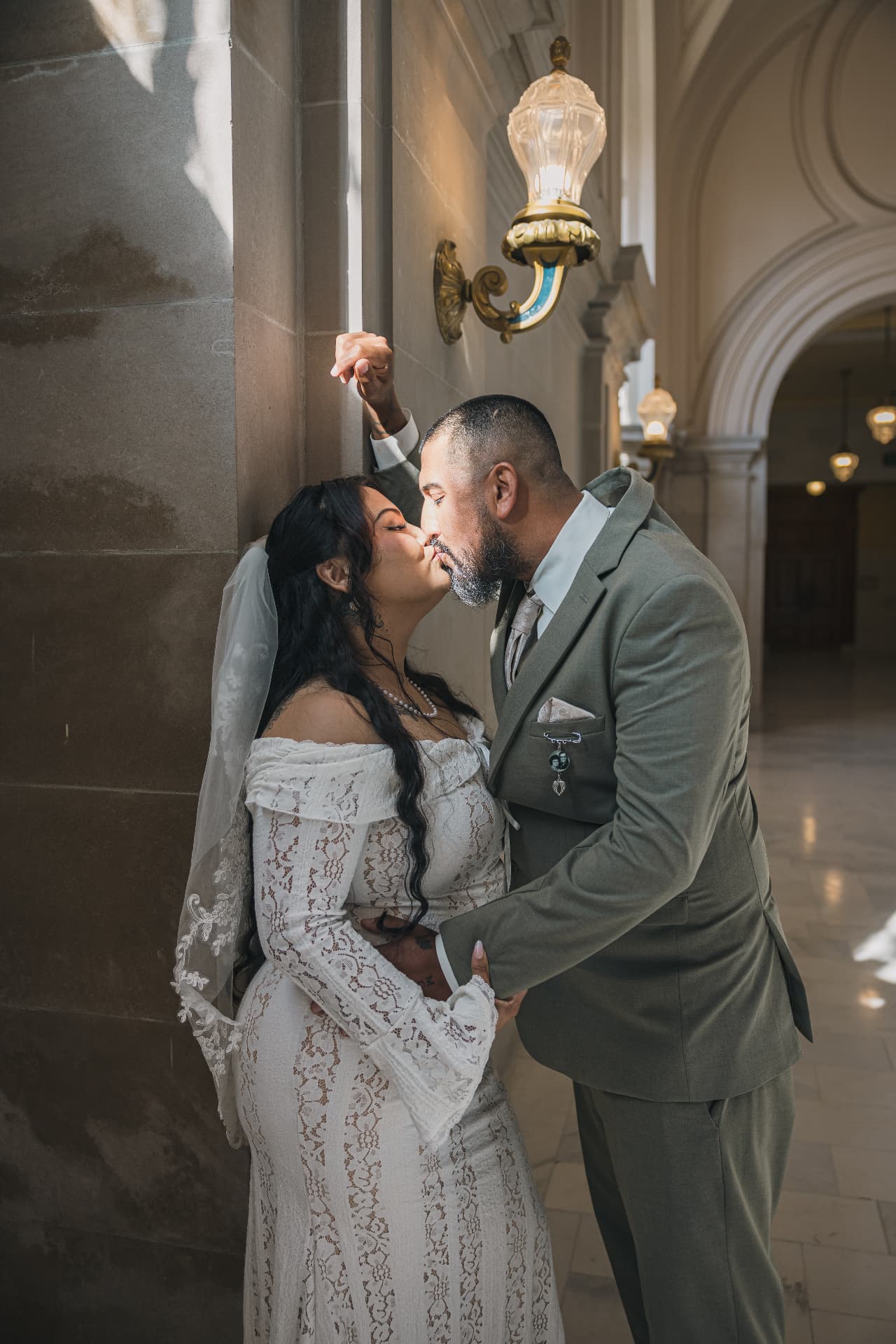 Bride and groom kissing in a dramatically lit corridor after their ceremony